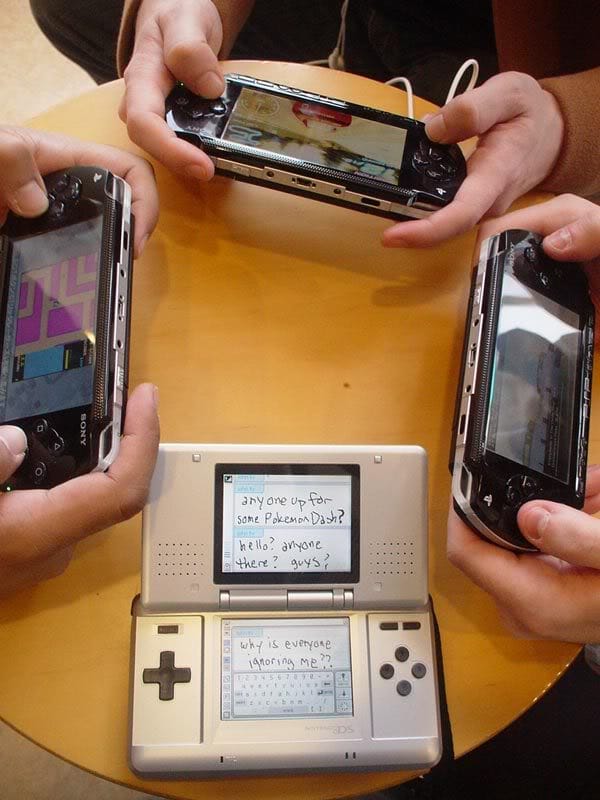 A meme that was popular in 2004 showing three people playing PSP while a fourth device, a Nintendo DS, sits on the table with a message on the screen that says "why is everyone ignoring me?"