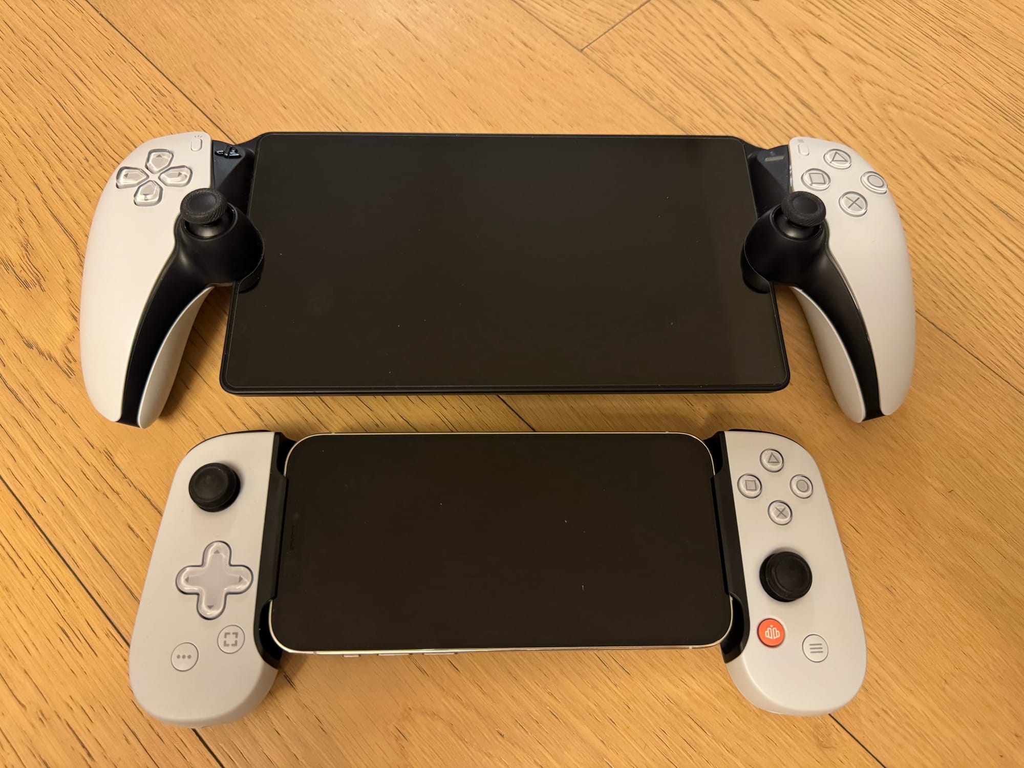 The PlayStation Portal handheld next to the much smaller iPhone 13 Pro with a controller attachment.