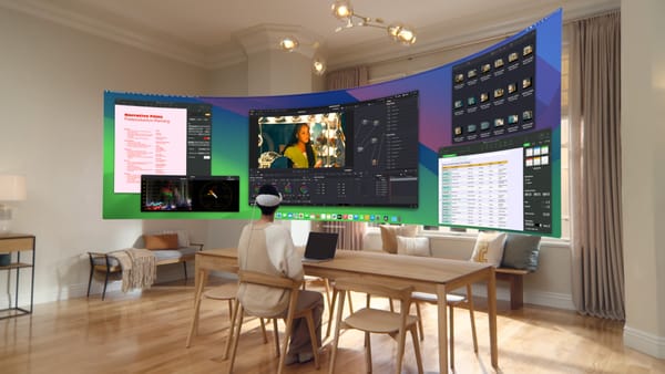 A woman sits in front of a virtual ultra wide Mac display projected by Apple Vision Pro.