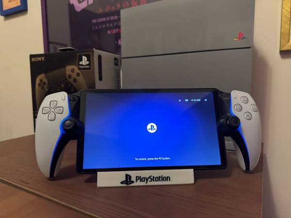 The PlayStation Portal handheld sits on a stand in front of a PlayStation 4 console.