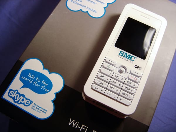 A white phone handset bearing the SMC logo sits atop a box that says Skype.